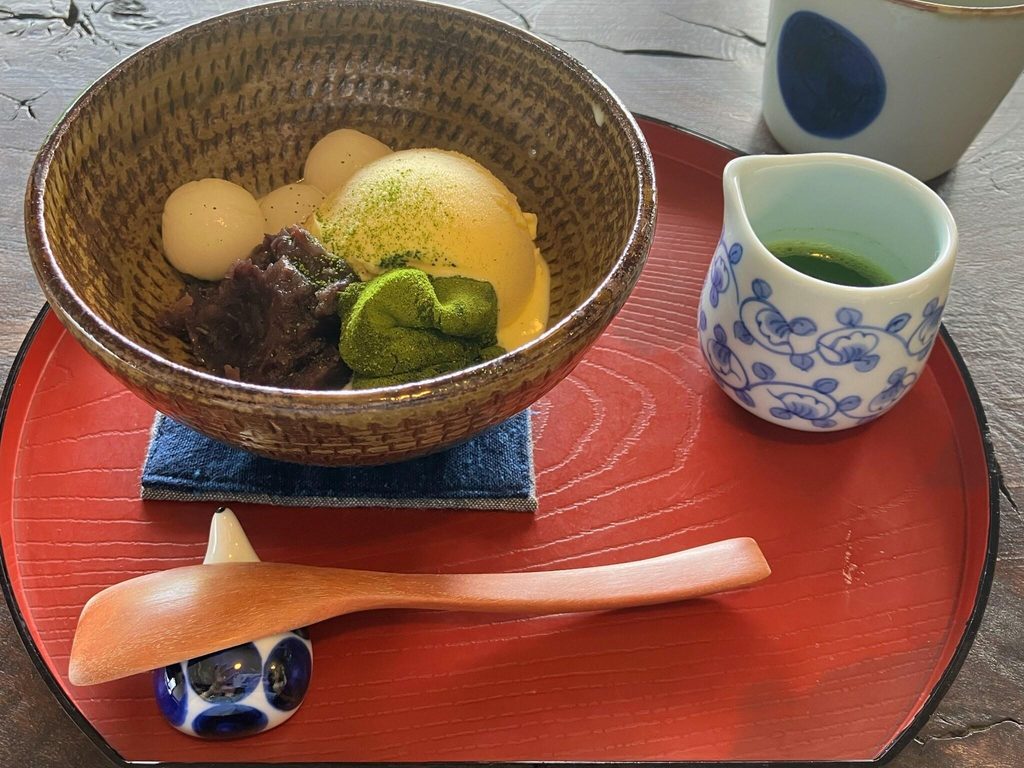 A matcha parfait served with a cup of matcha on a lacquer tray