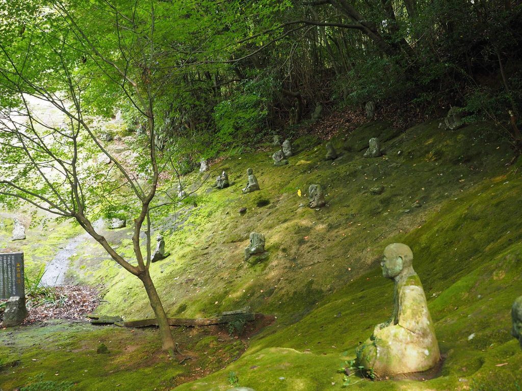 Hundreds of small stone arhat figures across a mossy hillside at Unganzenji Hundreds of small stone arhat figures across a mossy hillside at Unganzenji