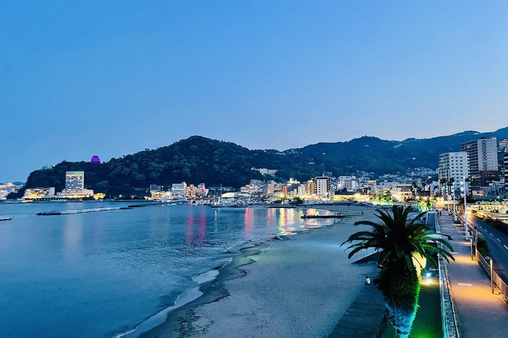 Atami's Sun Beach at dusk, with the hot-spring hotels lit up around the bay