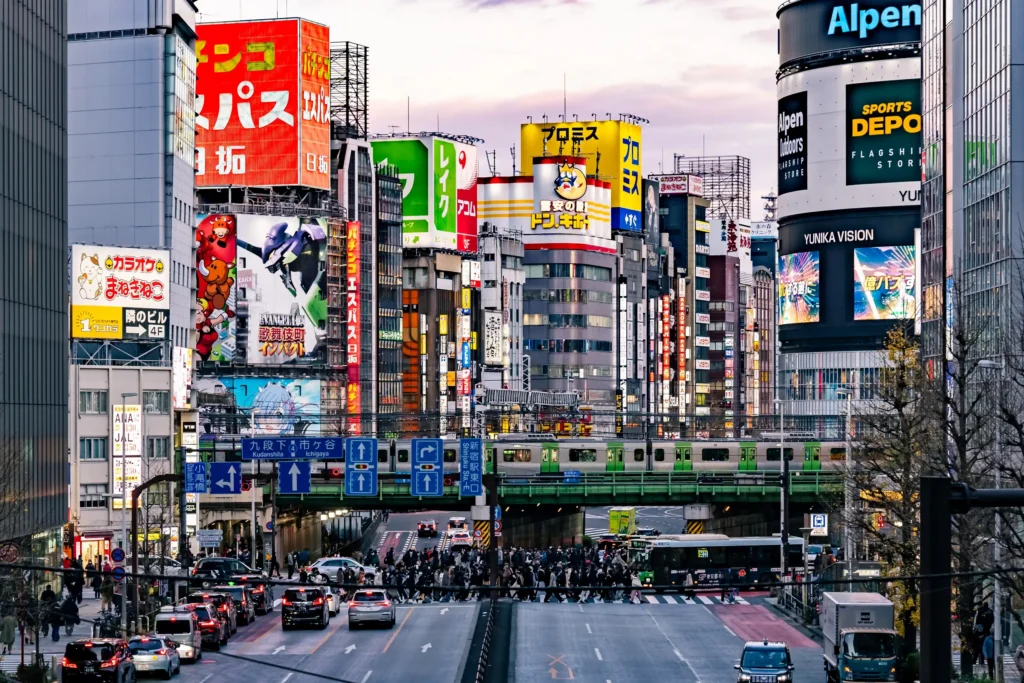 Yamanote Line train passing over a Shinjuku street lined with neon signs