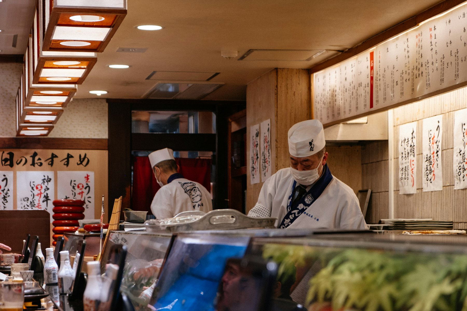 Sushi chefs preparing food behind a restaurant counter in Osaka