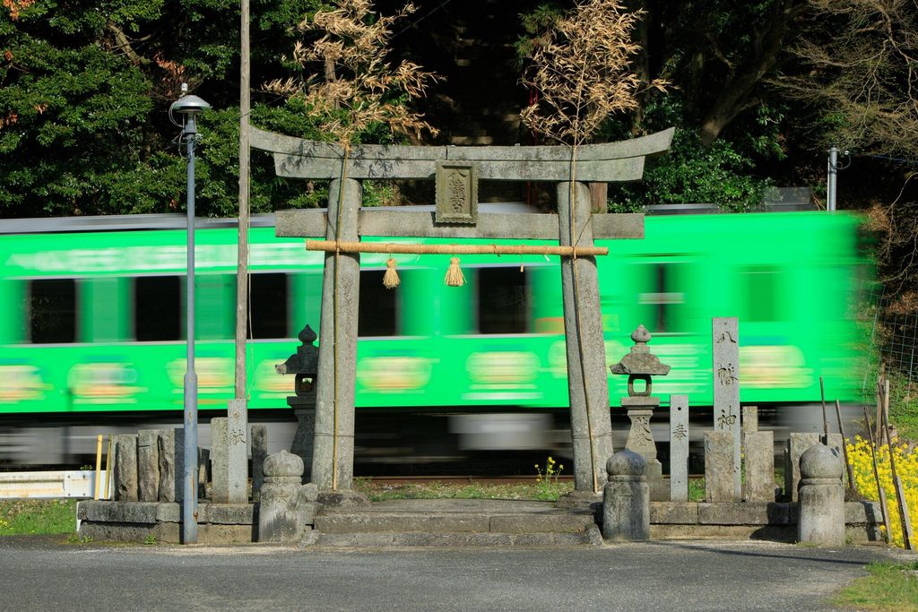 A train passing right behind the first torii of Sakiyama Hachiman Shrine, the Kyushu shrine whose approach crosses a railway A train passing right behind the first torii of Sakiyama Hachiman Shrine, the Kyushu shrine whose approach crosses a railway