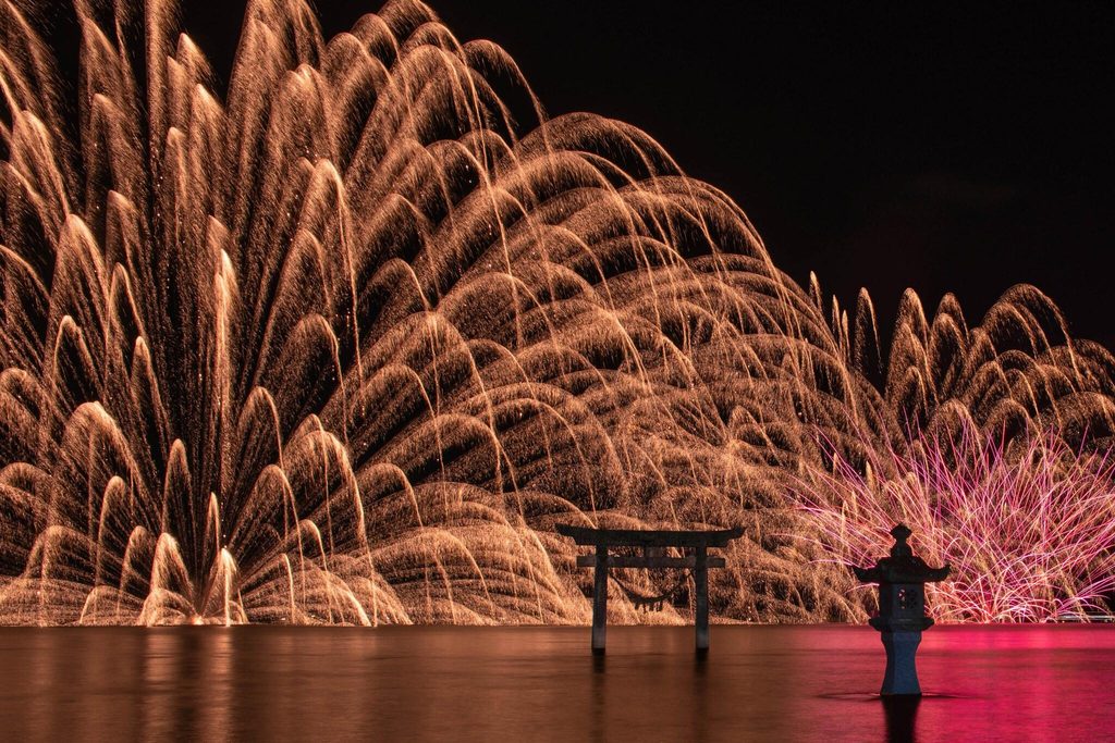 Fireworks behind the torii and stone lantern standing in the sea at Einoo Tsurugi Shrine, during the 2025 Shiranui sea fire festival Fireworks behind the torii and stone lantern standing in the sea at Einoo Tsurugi Shrine, during the 2025 Shiranui sea fire festival