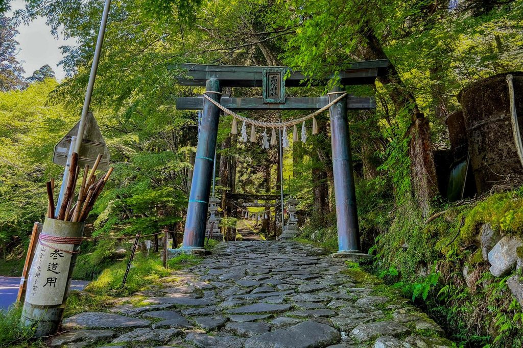 The torii at the start of the stone path to Takasumi Shrine on Mount Hiko, with a second torii and steps beyond The torii at the start of the stone path to Takasumi Shrine on Mount Hiko, with a second torii and steps beyond