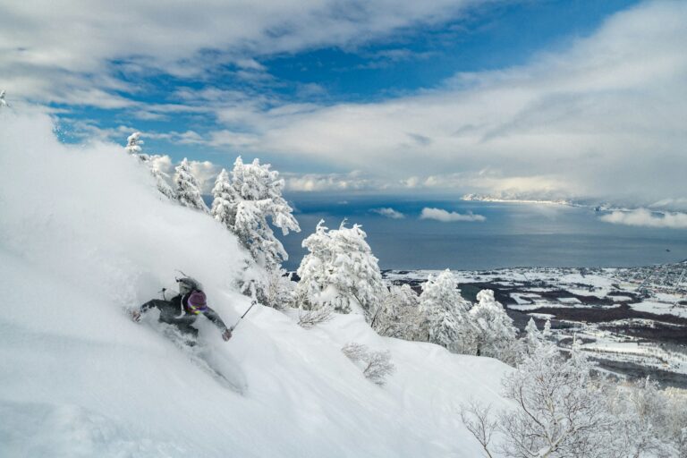 日本のスキーシーズン：北海道ニセコの深い新雪を滑るスキーヤー