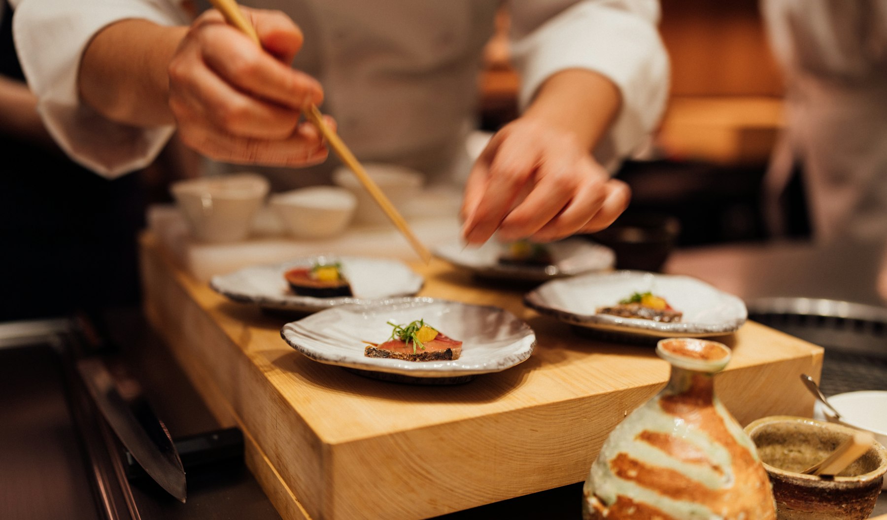 Chef plating food at a Japanese restaurant counter