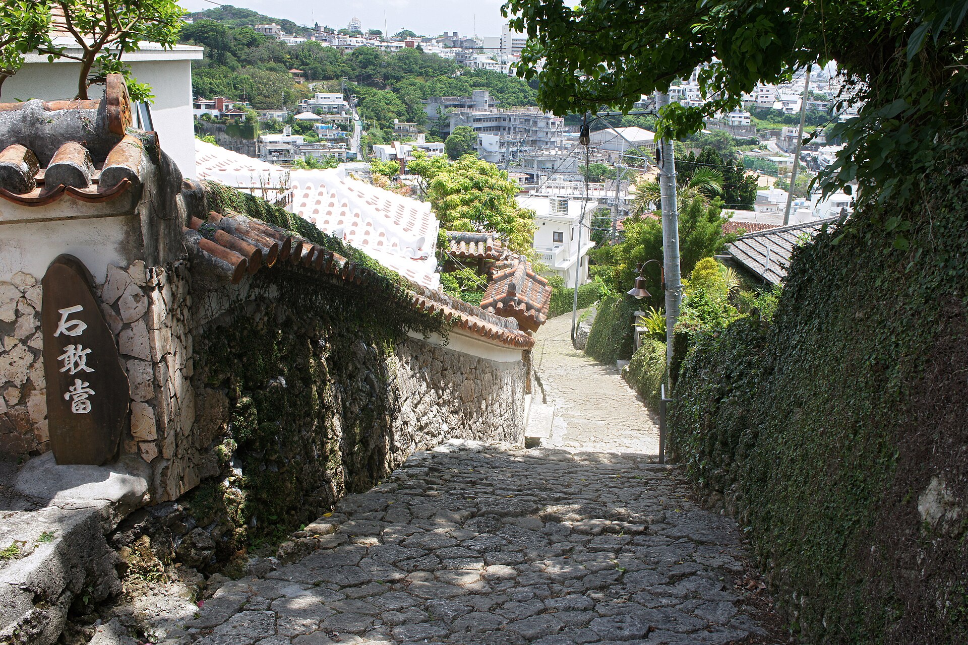 Kinjo-cho stone-paved road in Shuri, Naha, running downhill between old stone walls with the city below