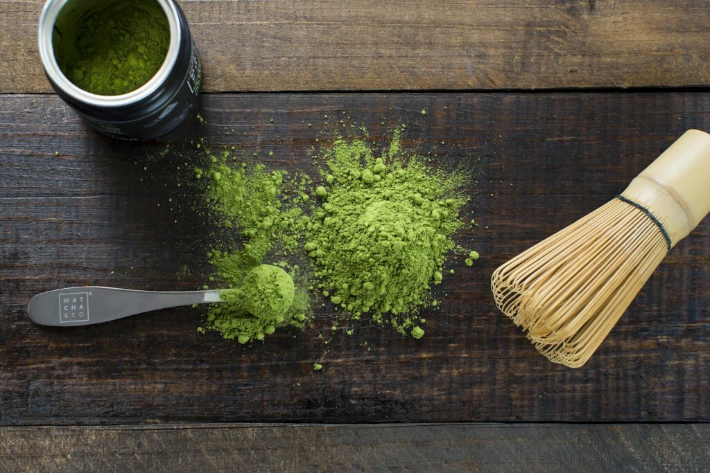Matcha powder and a bamboo whisk on a wooden board, the scent behind Fugazzi Matchabuya