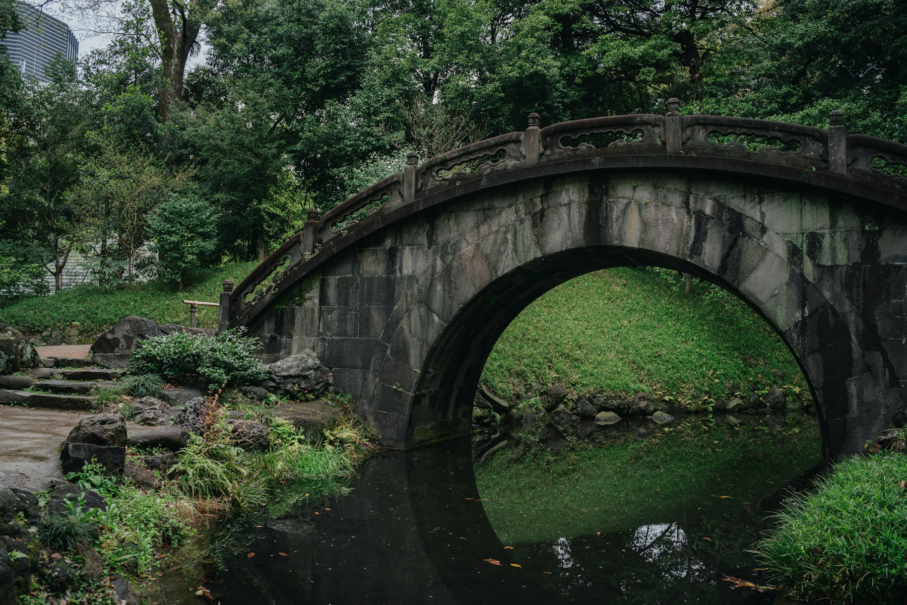 Stone arch bridge over a pond in Koishikawa Korakuen garden, Tokyo