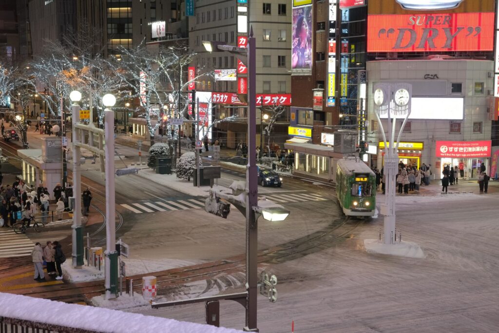 Snowy street at night with a tram and illuminated trees in winter