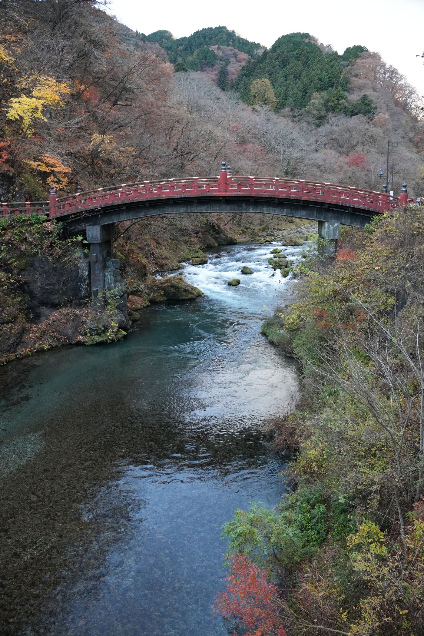 Nikko autumn leaves at Shinkyo Bridge: vermilion wooden bridge over the Daiya River with maples turning orange on the far bank