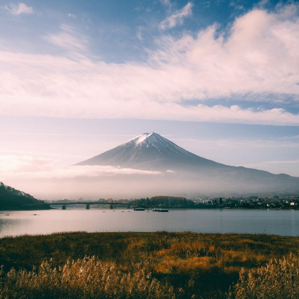 Snow-capped Mt Fuji above a misty Lake Kawaguchiko and bridge in Fujikawaguchiko