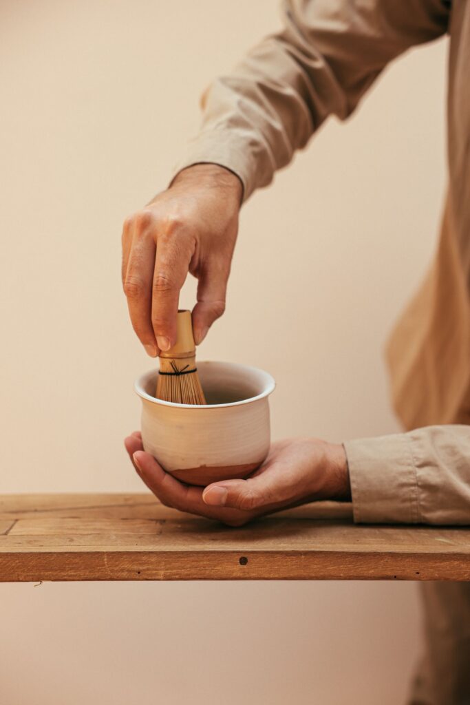 Hands whisking matcha in a bowl with a bamboo whisk, like the tea at the teamLab Kyoto teahouse